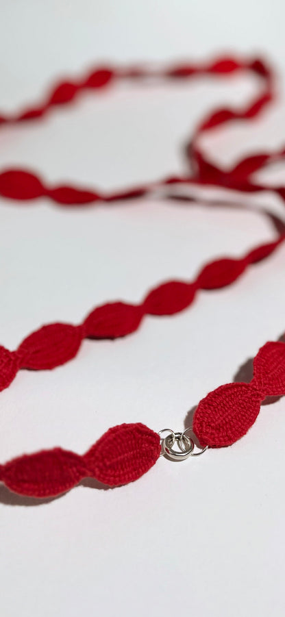 Close view of ending detail in Sterling Silver of an interwoven cotton ovals necklace on a white background
