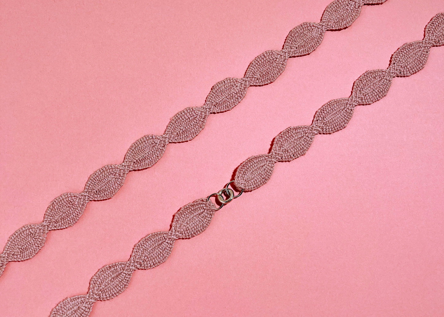 Close view at the fabric and endings detail of a pink cotton interwoven ovals necklace with Sterling Silver endings placed in a double loop 
