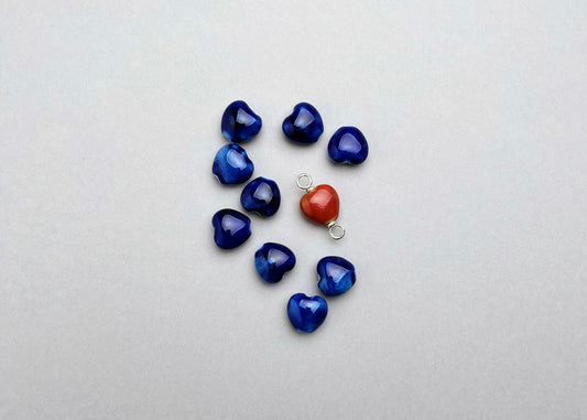 Overhead view of a group of porcelain blue chunky_hearts_and_red_one with_Sterling silver endings on a grey background