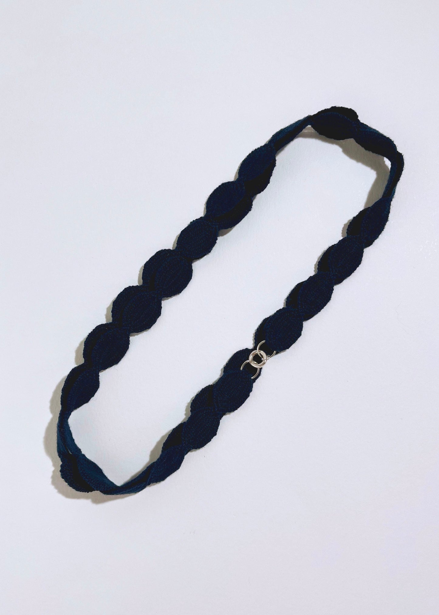 Overhead view of a navy cotton woven ovals necklace with Sterling Silver endings placed in double loop on a white background