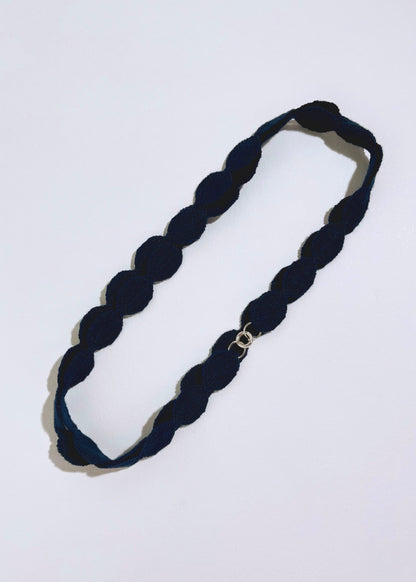 Overhead view of a navy cotton woven ovals necklace with Sterling Silver endings placed in double loop on a white background