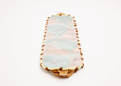 Front view of an open reversible cotton woven strap bracelet with tulip motif in light blue and embroidered borders in brown and butter yellow with Sterling Silver looped endings detail on a white background.
