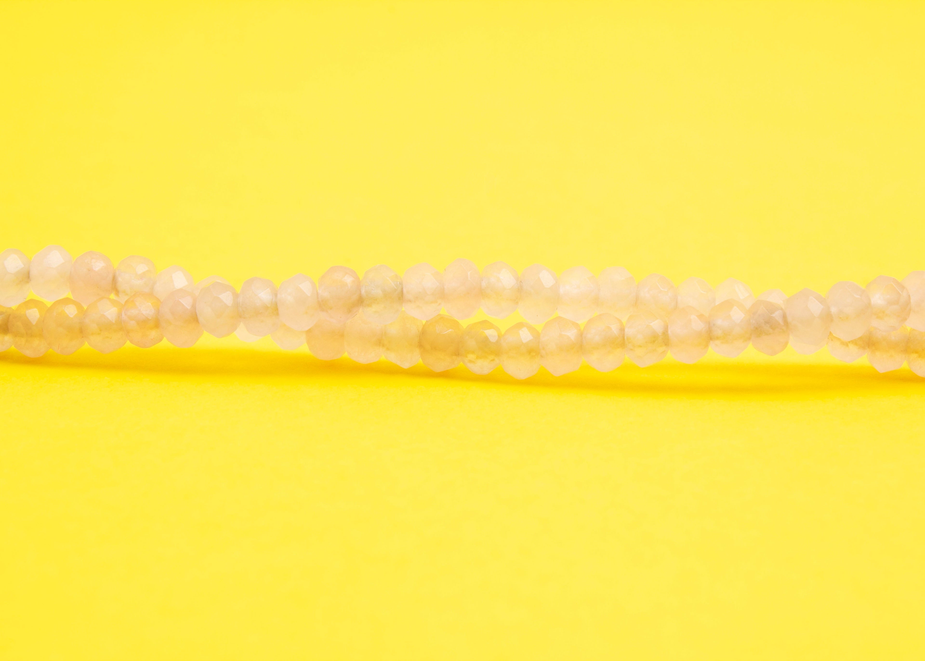 Front view beads detail of a pink quartzite beaded necklace with Sterling Silver looped endings on a yellow background