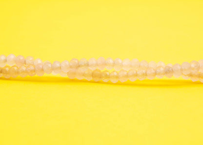 Front view beads detail of a pink quartzite beaded necklace with Sterling Silver looped endings on a yellow background