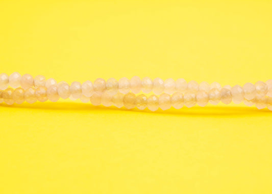 Front view beads detail of a pink quartzite beaded necklace with Sterling Silver looped endings on a yellow background