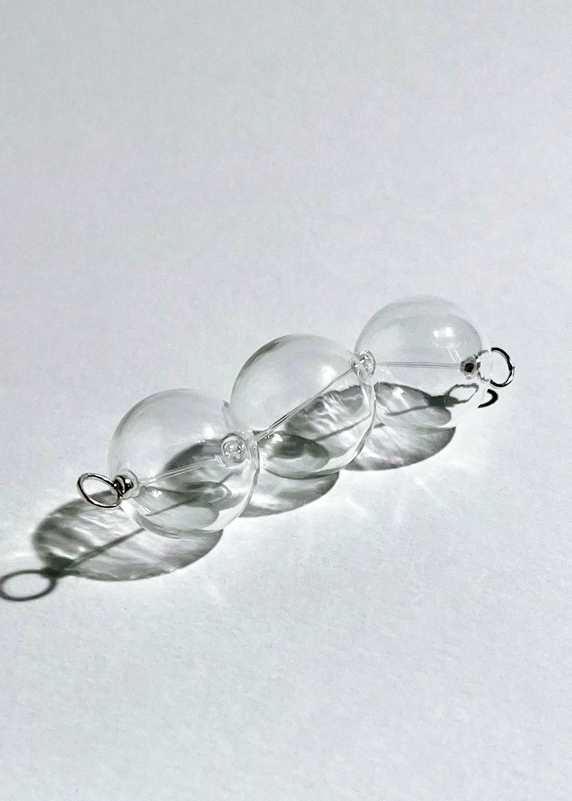 Diagonal front view of a chunky clear glass beaded chainlet under headlight with Sterling Silver looped endings in a white background