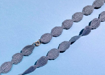 Overhead close look at fabric and endings of a sky blue cotton woven ovals necklace with Sterling Silver endings placed diagonally on a sky blue background