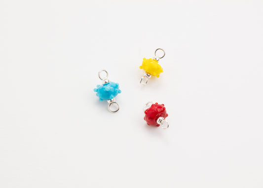Front view of a trio of urchin lampwork glass charms with Sterling Silver ends in a white background