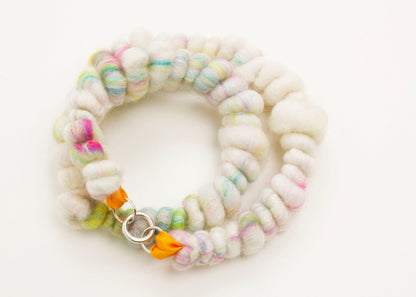 Plan view  detail  of a wool yarn necklace in cream, with bright colourful accents and Sterling Silver looped endings on a white background