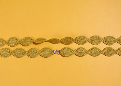 Overhead close look at the fabric and endings of a yellow cotton woven necklace placed horizontally with sterling silver endings on a yellow background