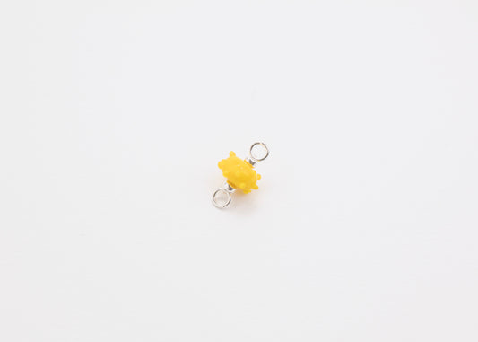 Diagonal view of a yellow urchin lampwork glass charm with Sterling Silver ends in a white background